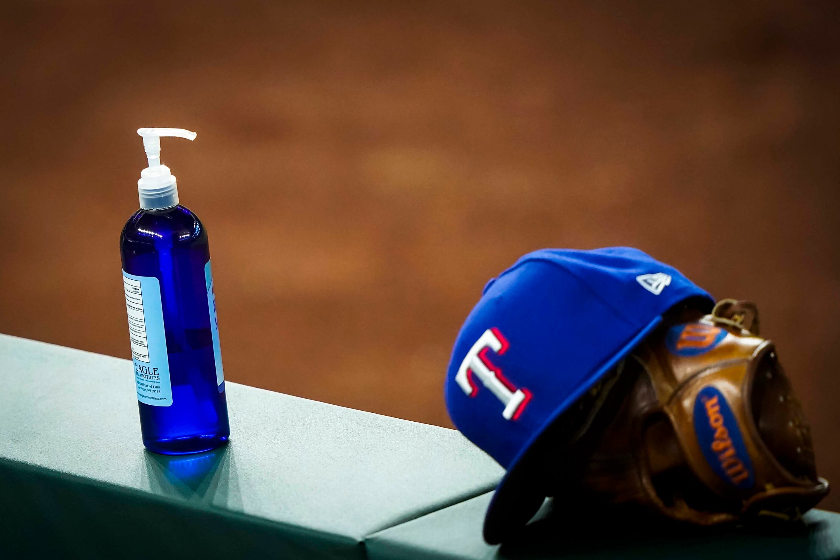 A bottle of hand sanitizer rests on the dugout railing during a Texas Rangers Summer Camp ...
