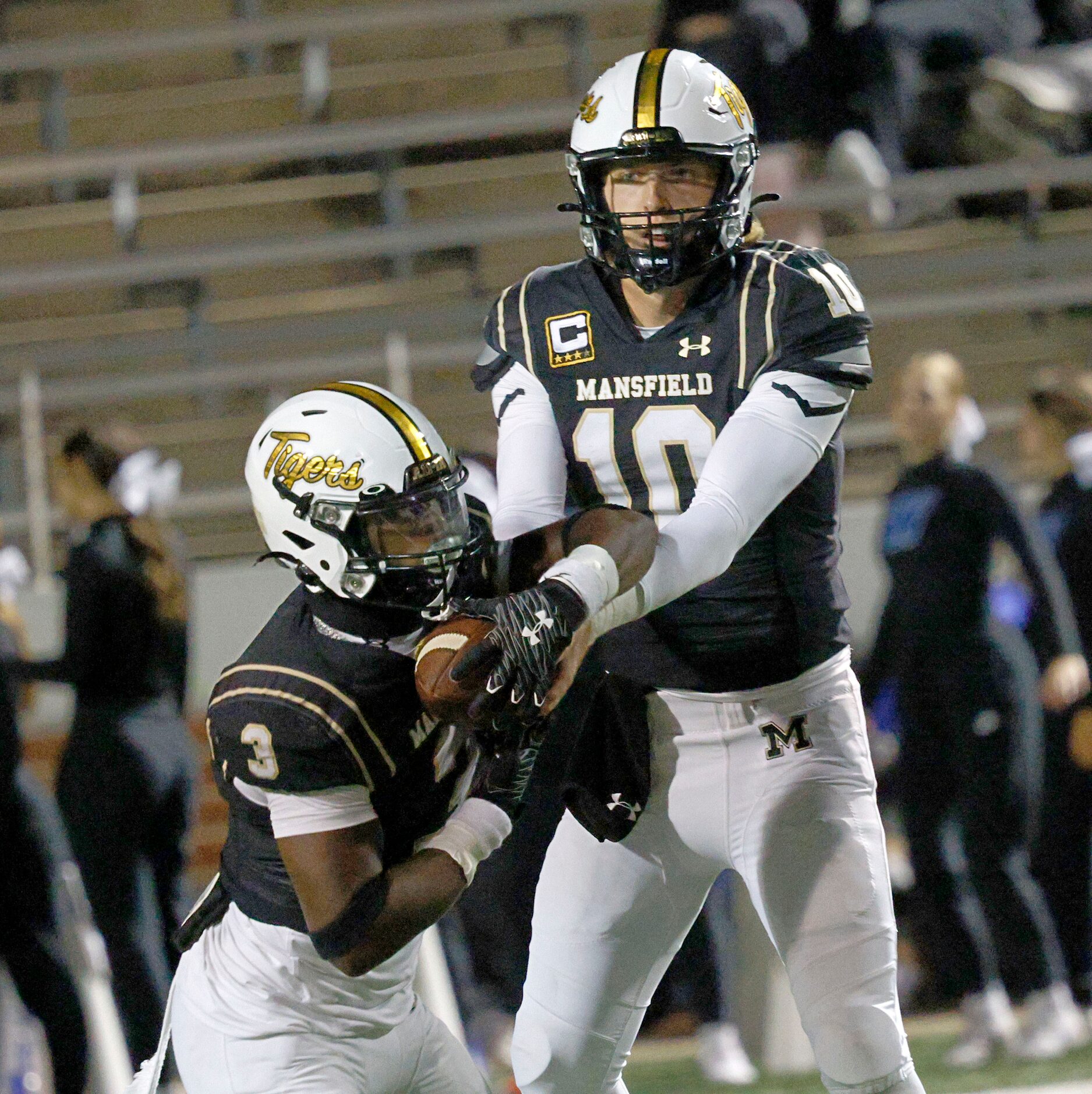 Mansfield's quarterback Braxton Van Cleave (10) hands off to Mansfield's Teddy Clark (3) in...