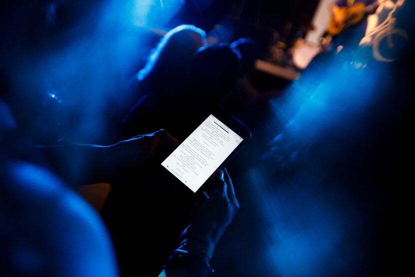 Meryl Evans pulls out her cellphone to follow along with the song lyrics during a concert by...