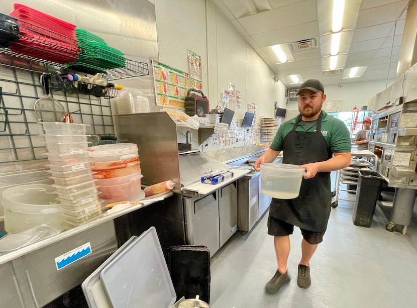 Derek Buie, district manager of Marco's Pizza, brings a dirty dish to a neat pile of sullied...