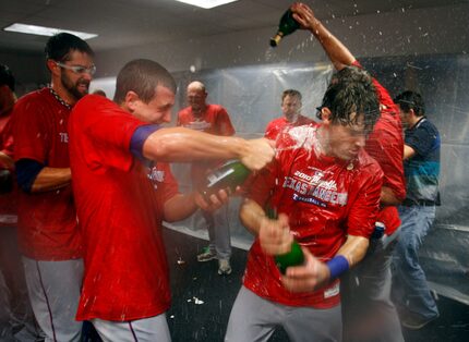 FILE - Derek Holland (left) sprays Ian Kinsler (center) with champagne as the Rangers...