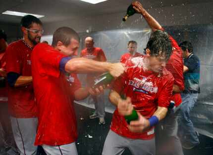 FILE - Derek Holland (left) sprays Ian Kinsler (center) with champagne as the Rangers...