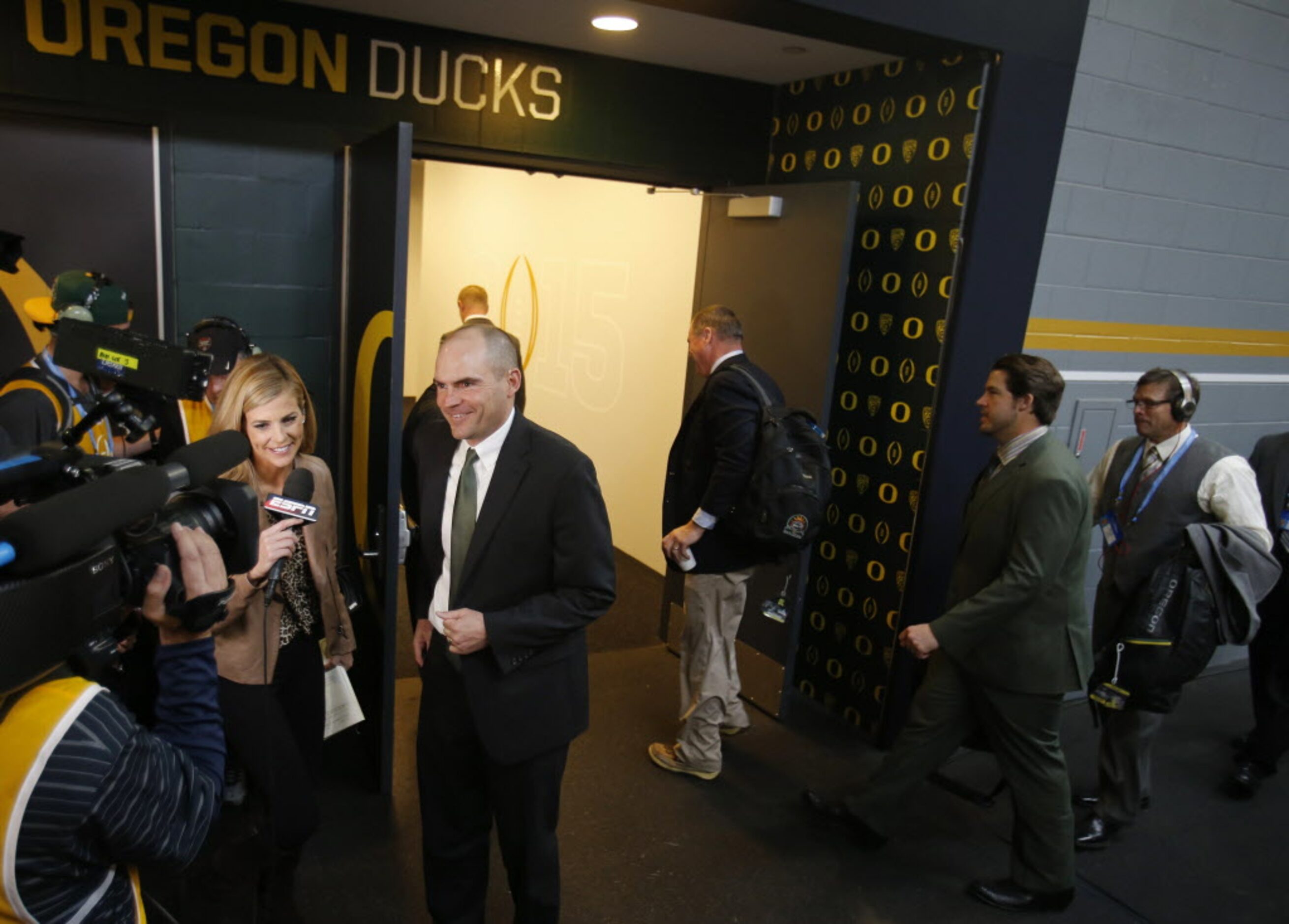 Oregon Ducks head coach Mark Helfrich conducts an interview as the rest of the team makes...