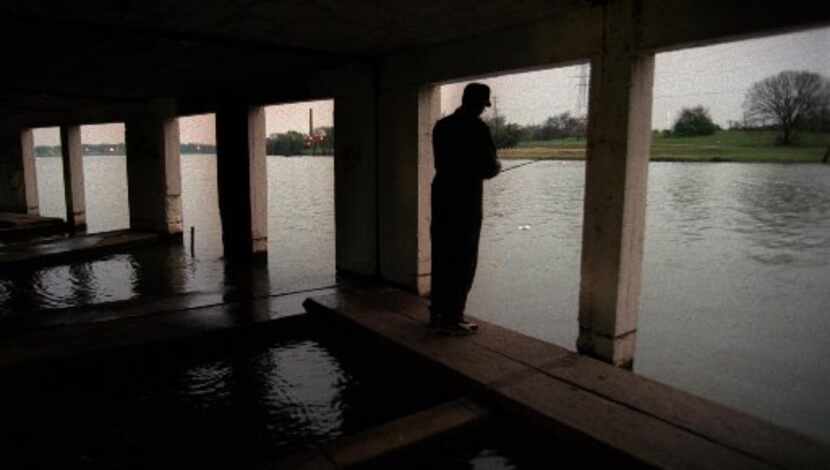  A long-ago photo of a man fishing from the old White Rock Lake boathouse on the T&P Hill..