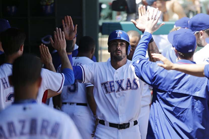 Texas Rangers left fielder Ian Desmond (20) is congratulated by teammates after scoring a...
