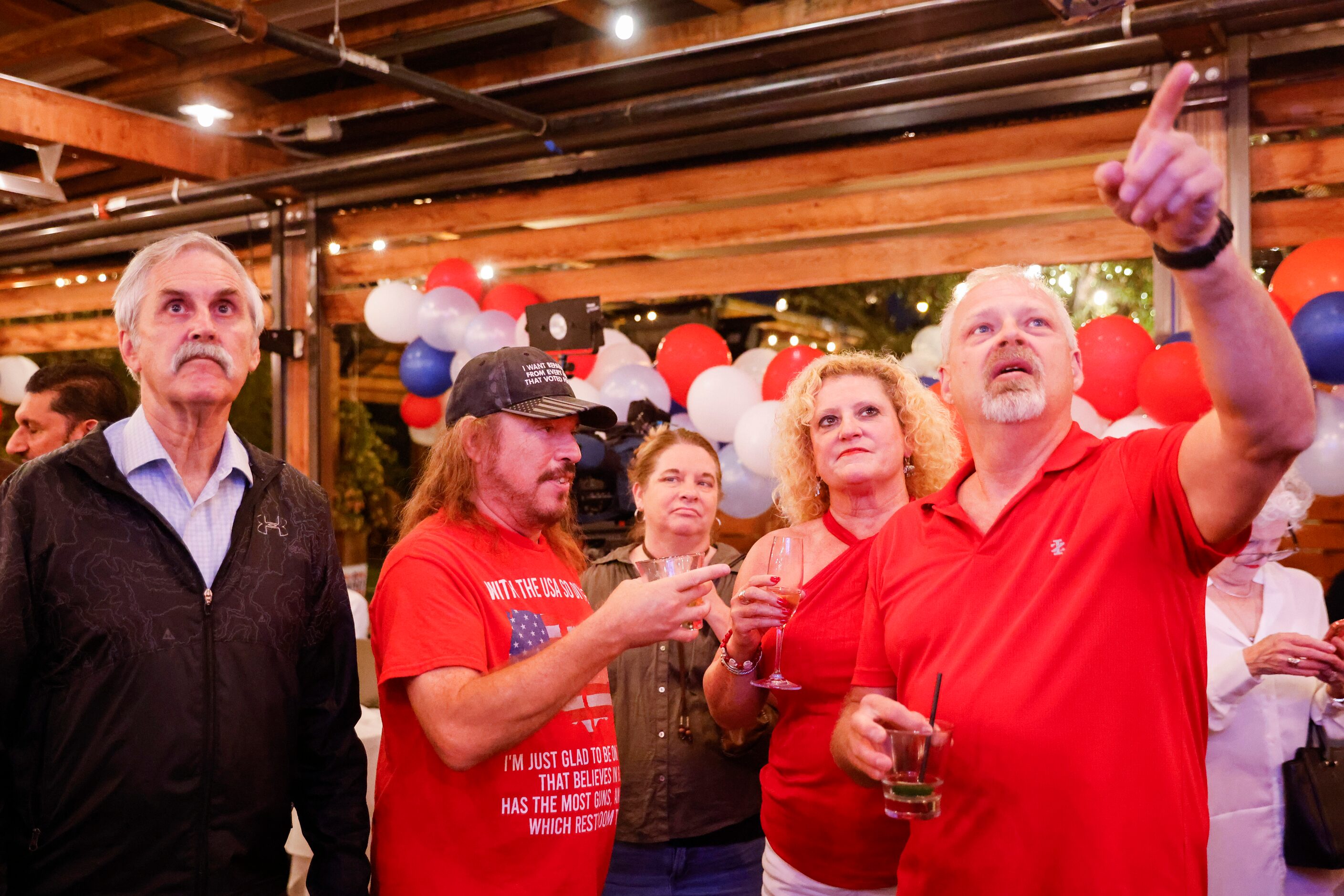 Others watch as Chris Johnson, right, of Arlington points towards the television following...