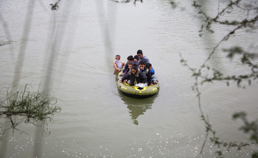 Two guides lead a raft full of migrants from Honduras and Guatemala across the Rio Grande in...