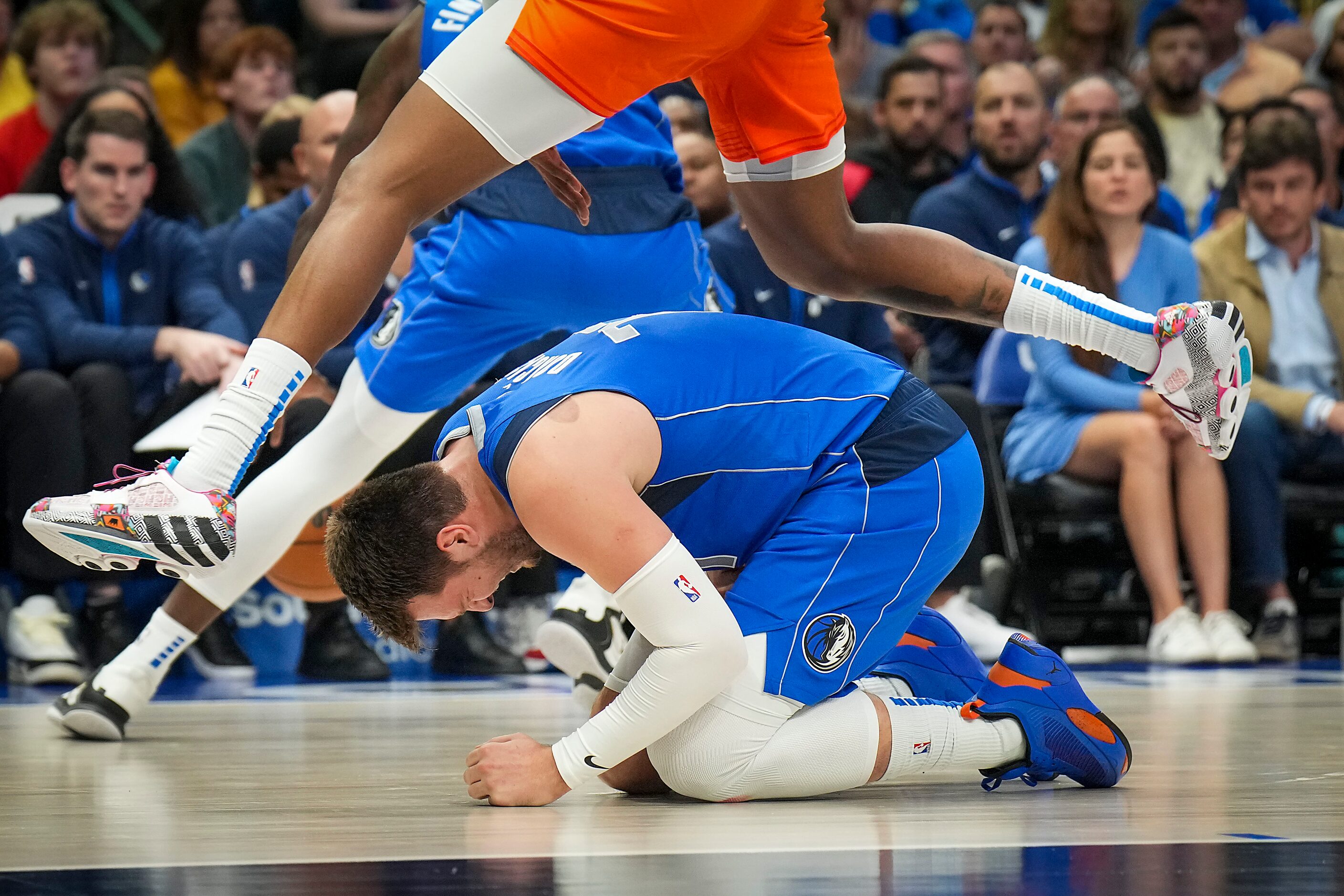 Dallas Mavericks guard Luka Doncic (77) kneels on the floor after a collision during the...