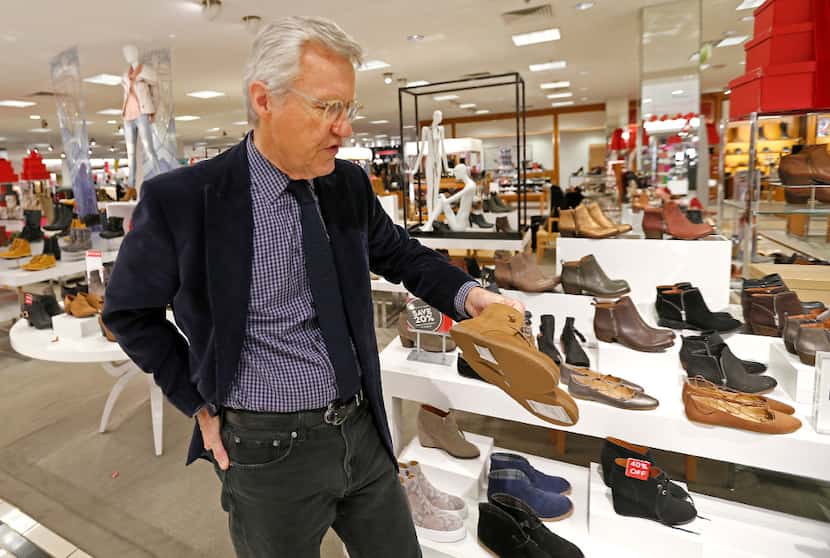 Allen Questrom talks about a pair of women's shoes while touring at the Macy's department...