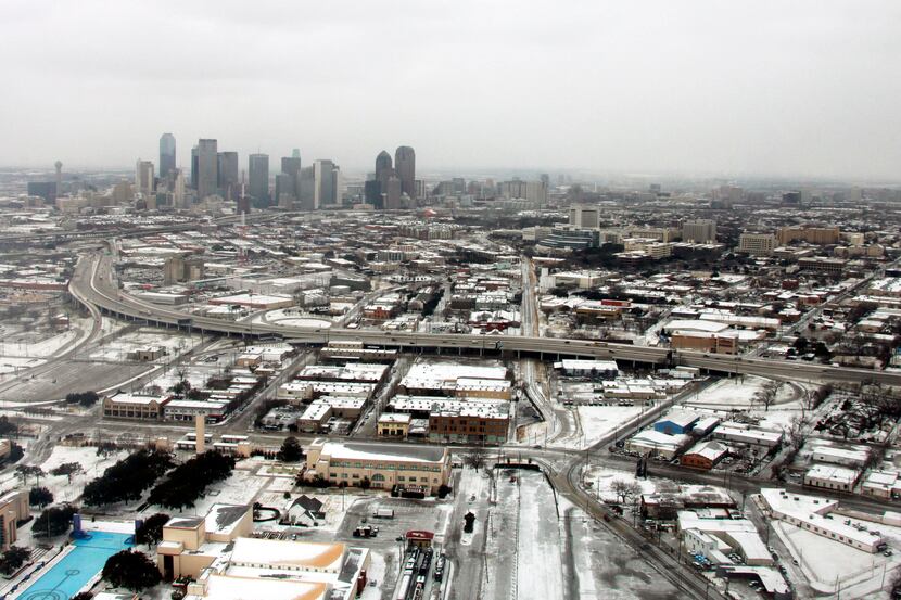 An aerial view of the snow with the Dallas skyline in the background.