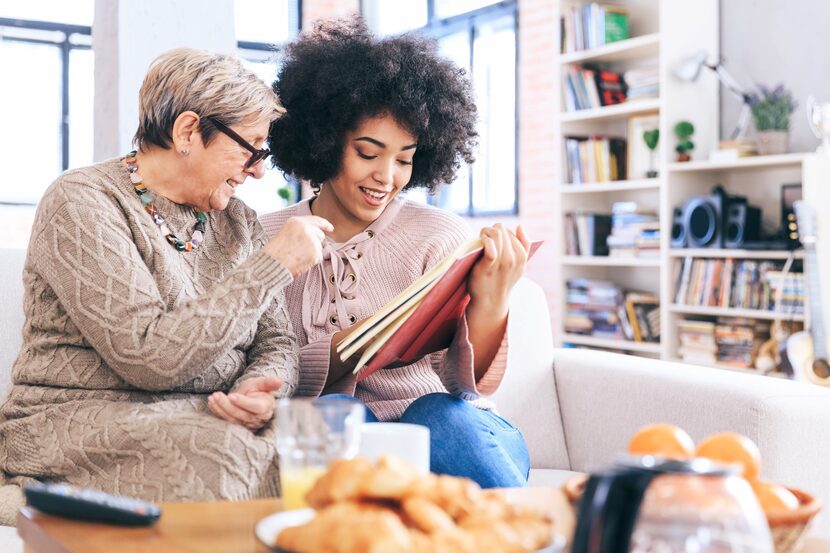 Older mother and younger daughter read a book together.