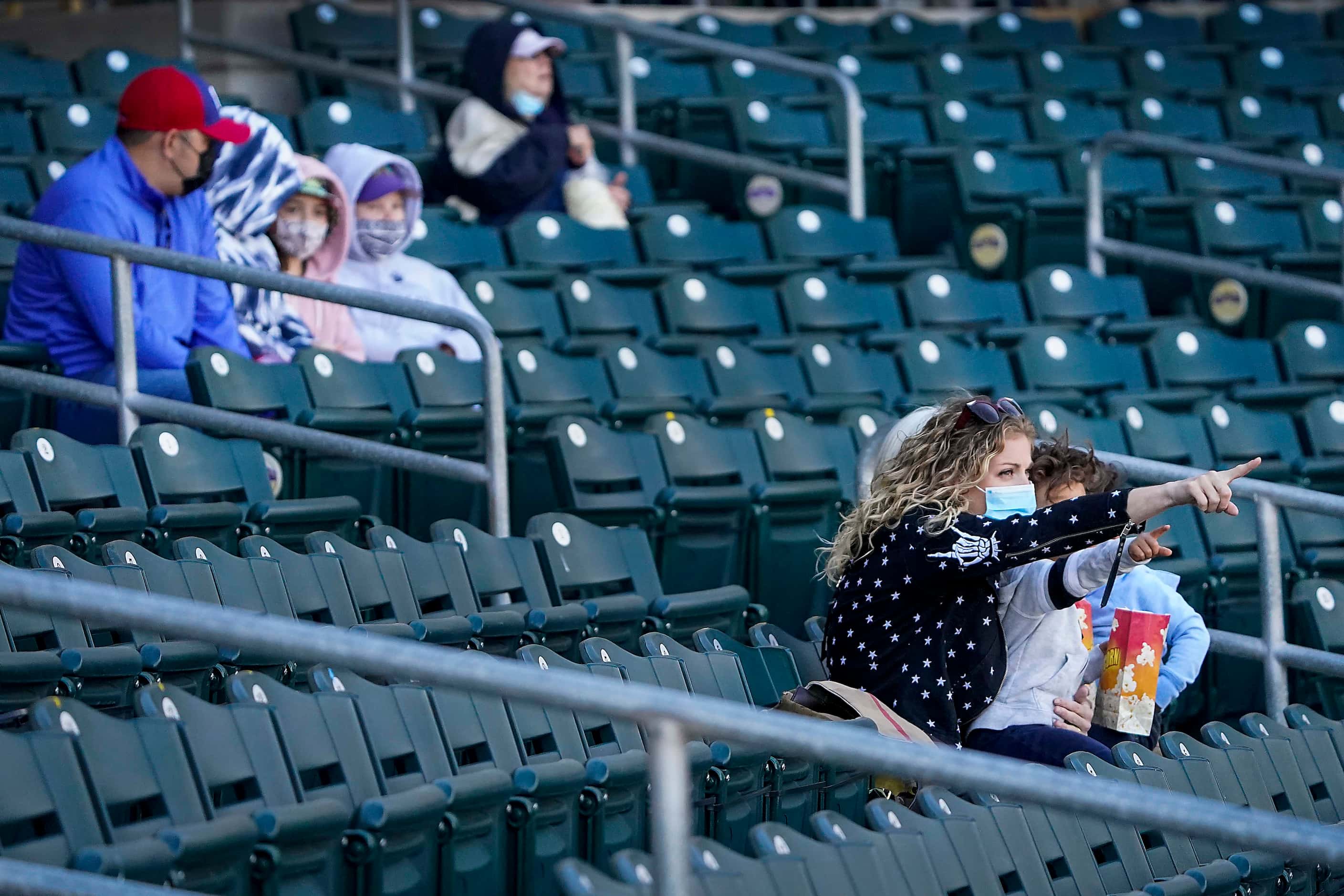 Fans sit in socially distant “pods” as they watch a spring training game between the Texas...