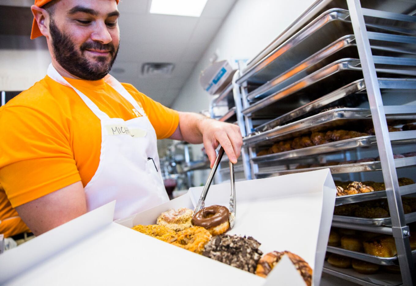 Rise Biscuits Donuts employee Michael Cutler boxes donuts for a customer during a grand...