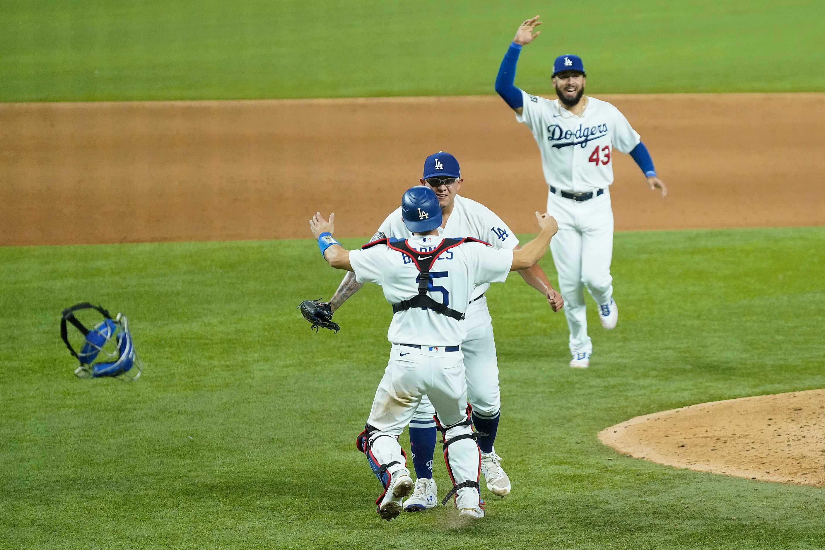 Los Angeles Dodgers players rush to join pitcher Julio Urias and catcher Austin Barnes as...