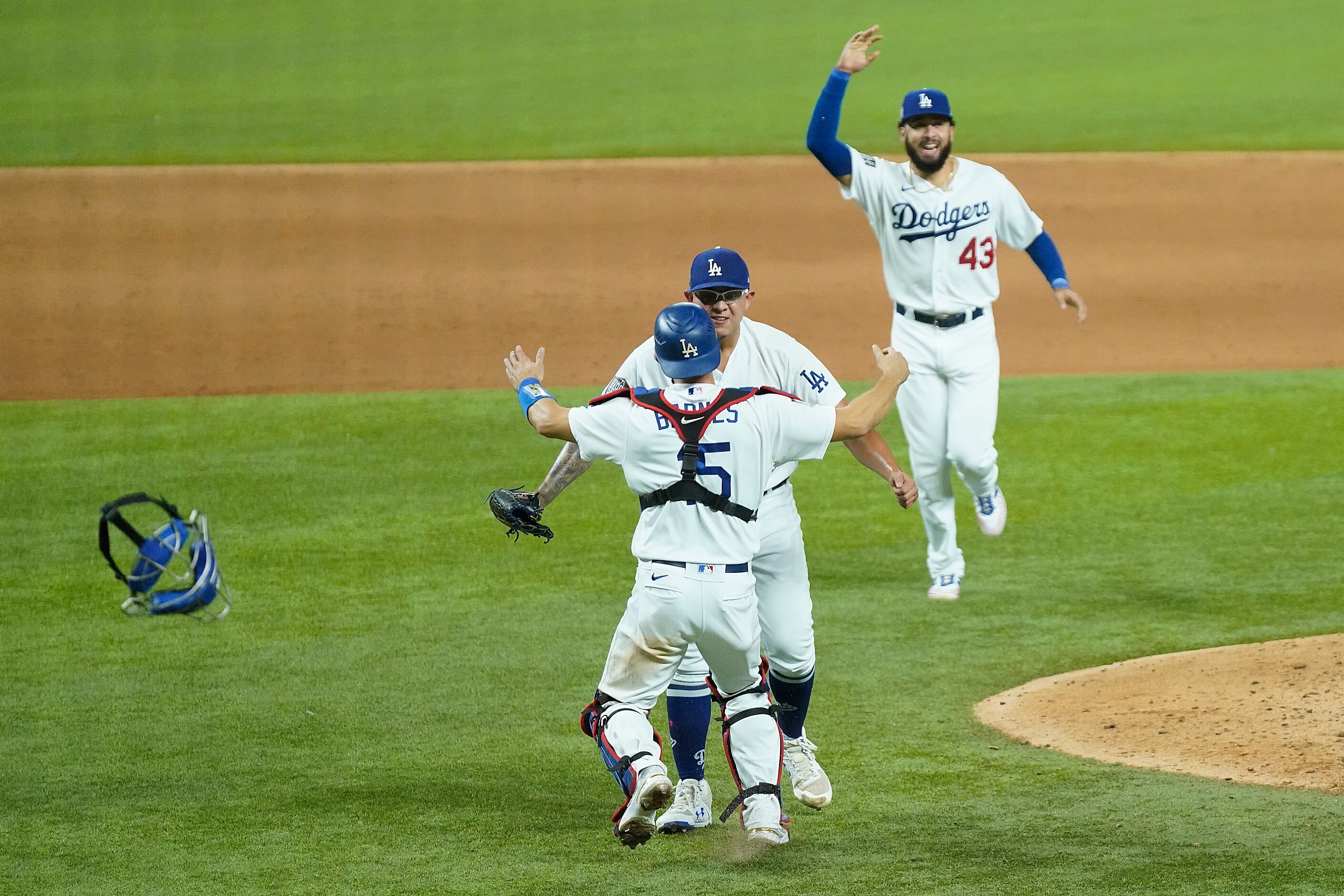 Los Angeles Dodgers players rush to join pitcher Julio Urias and catcher Austin Barnes as...