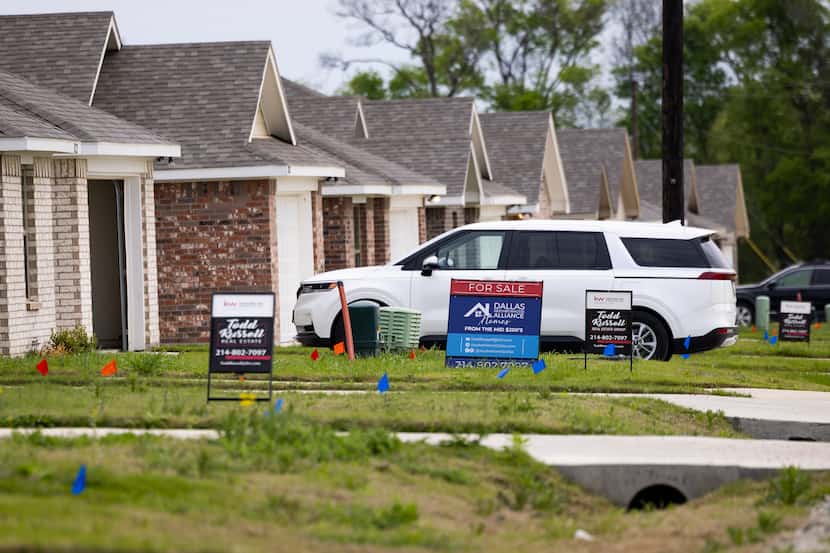 For sale signs in front of a home that are part of a residential development by Dallas...