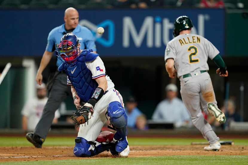 The ball gets away from Texas Rangers catcher Sam Huff as Oakland Athletics' Nick Allen...