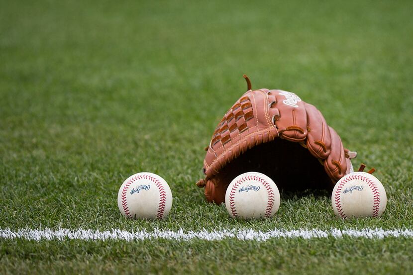 Balls rest next to the glove of a Rangers pitcher before a spring training game at Surprise...