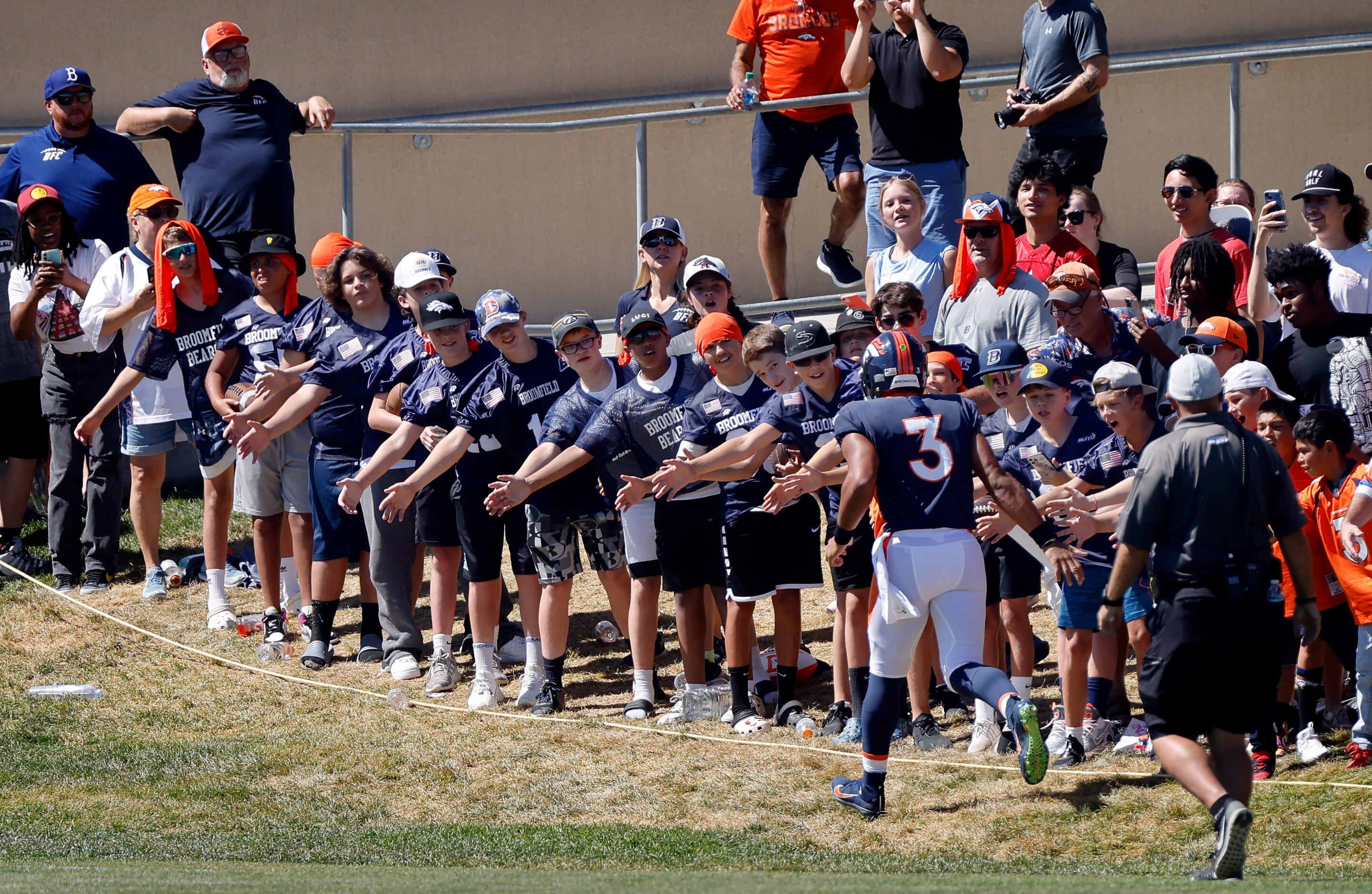 Denver Broncos quarterback Russell Wilson (3) slaps hands with fans as he runs onto the...