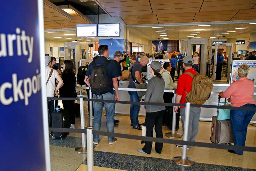 Travelers wait to enter a TSA security checkpoint at DFW International Airport.