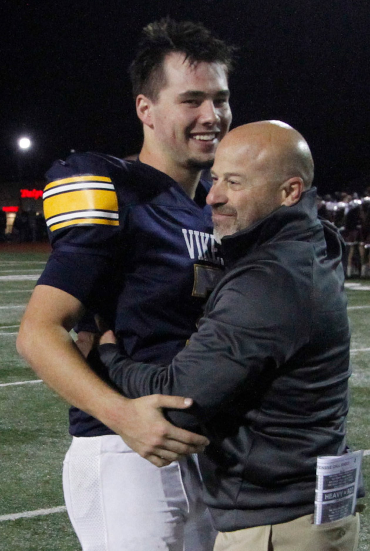 Arlington Lamar head coach Laban DeLay shares a hug with Vikings quarterback Jack Dawson (7)...