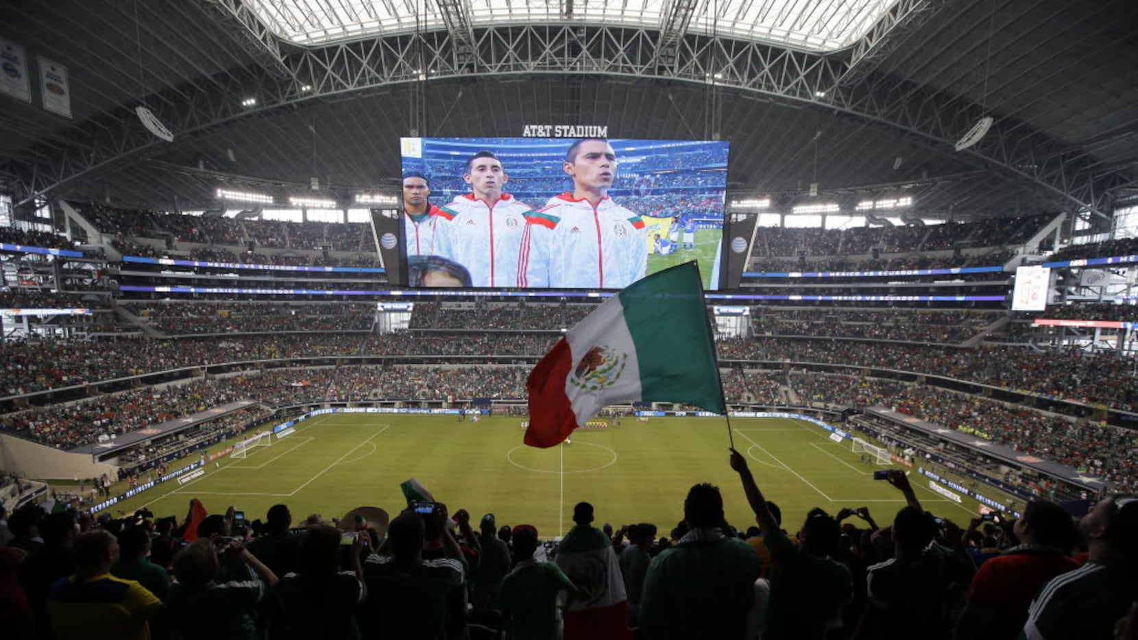 A Mexico fan waves a national flag during the playing of the Mexican national anthem at AT&T...