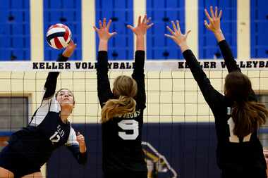 Keller’s Anna Flores (12) spikes the ball against Southlake Carroll’s Taryn Barnes (9) and...