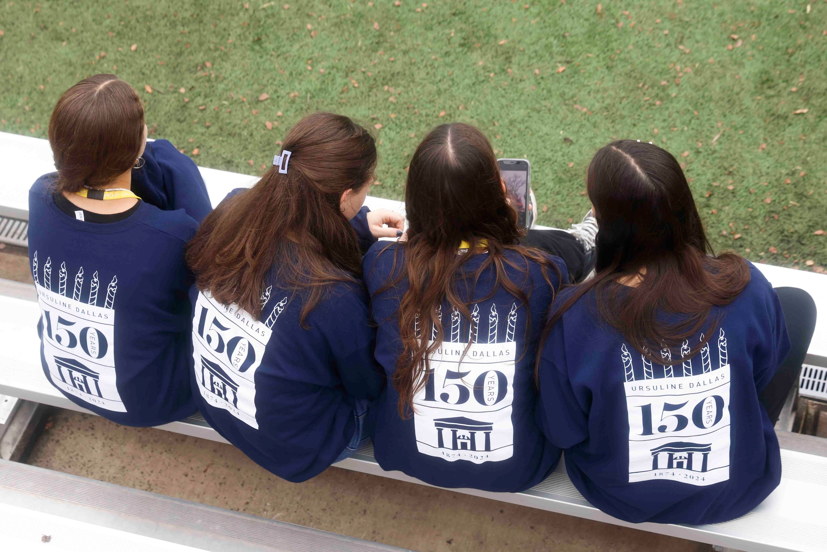 Students wearing Ursaline Dallas hoodie sit on the bench during the 150th anniversary...