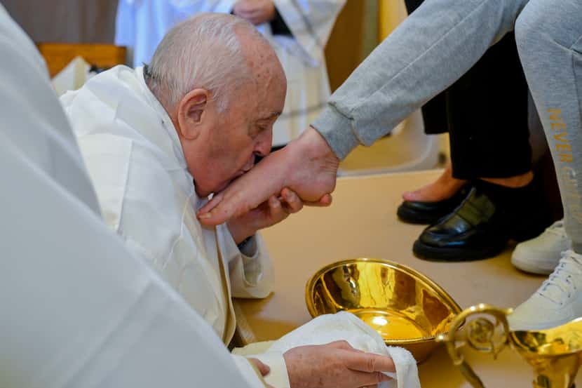 En esta imagen cortesía del Vaticano, se ve al papa Francisco besar el pie de una mujer...