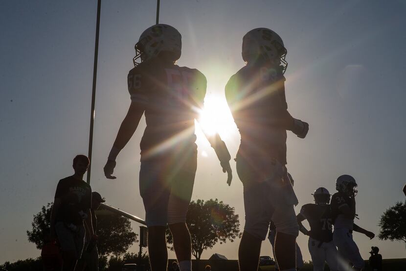 The sun begins to set behind the All Saints' Episcopal School varsity football team as they...