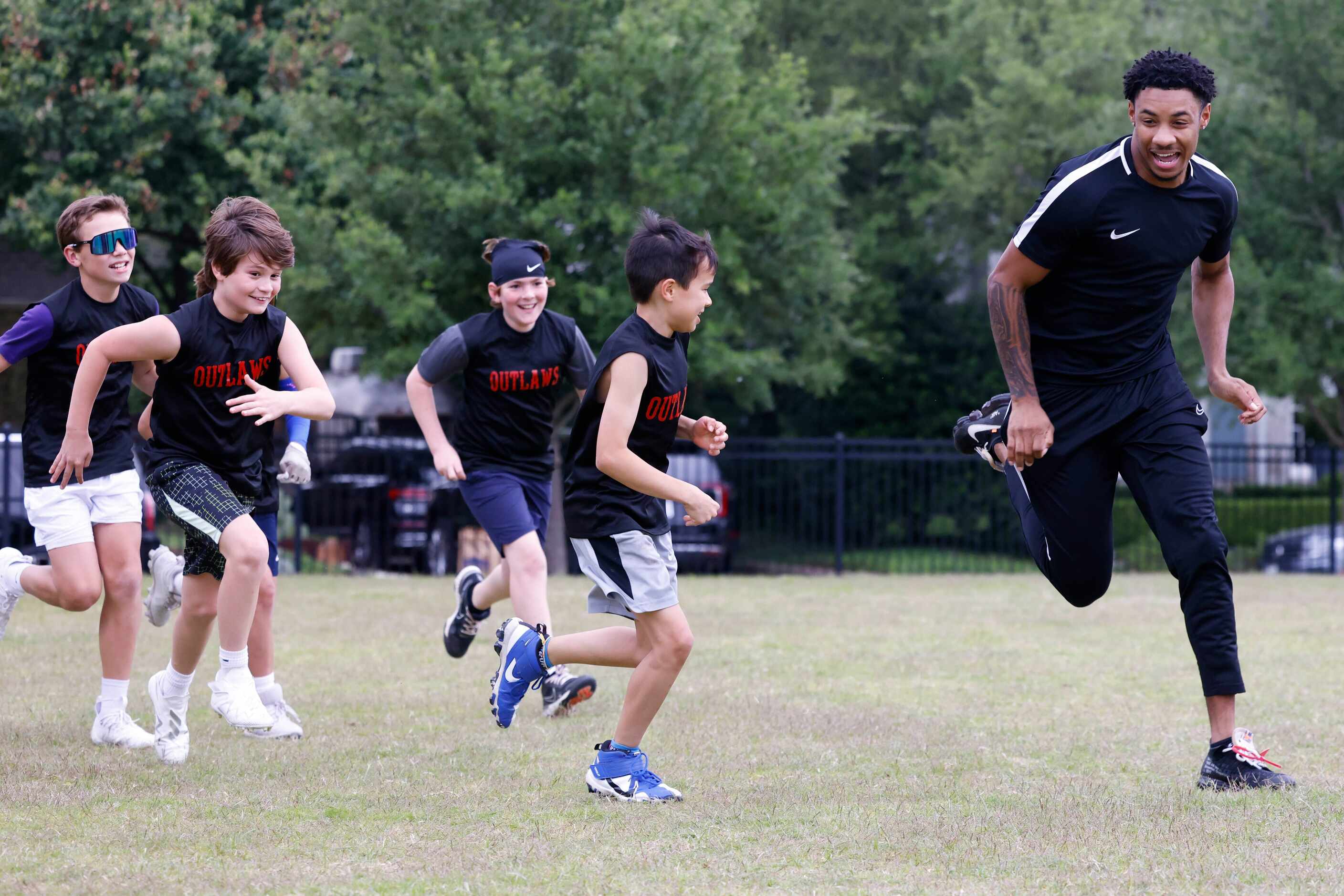 SMU’s Chris Megginson (right) runs past the kids during a special session of football drills...