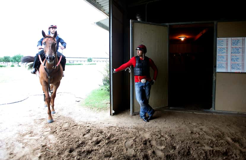 Exercise rider Diego Cervantes waits during a break at the track in the barns at Lone Star...
