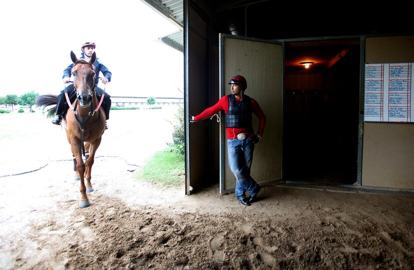 Exercise rider Diego Cervantes waits during a break at the track in the barns at Lone Star...