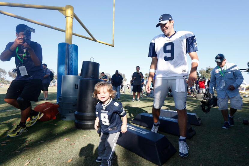 Tony Romo watches his son Hawkins as he climbs over equipment after the afternoon practice...