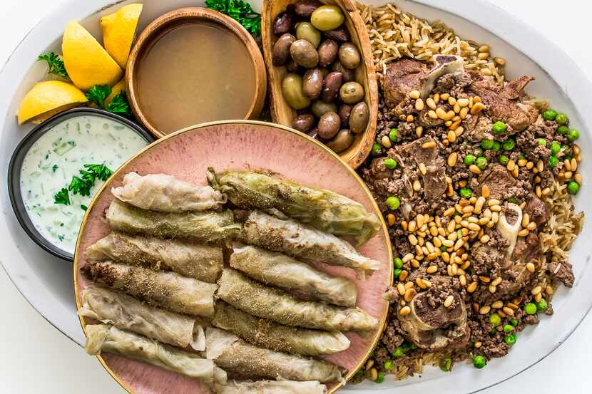 Lamb with rice is served with cabbage rolls, yogurt sauce and olives.