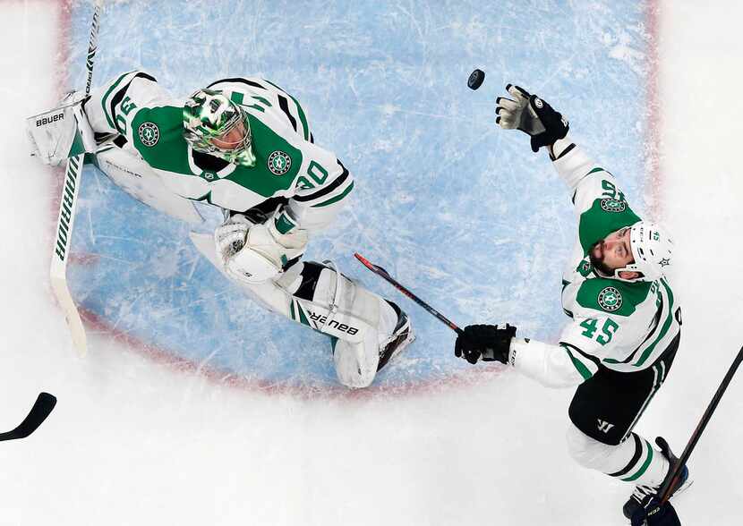 Dallas Stars goaltender Ben Bishop (30) and defenseman Roman Polak (45) eye an airborne puck...