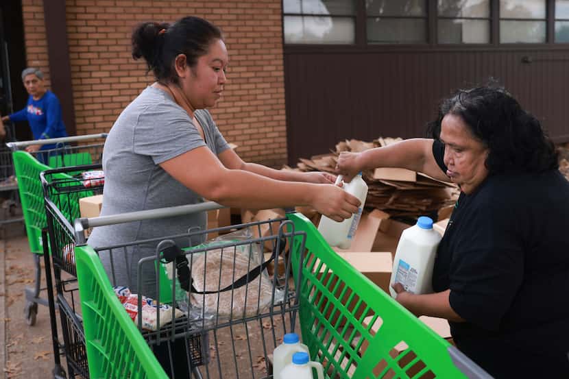 Volunteers Lorena Morales, left, and Trinidad Garcia fill grocery carts with food pantry...