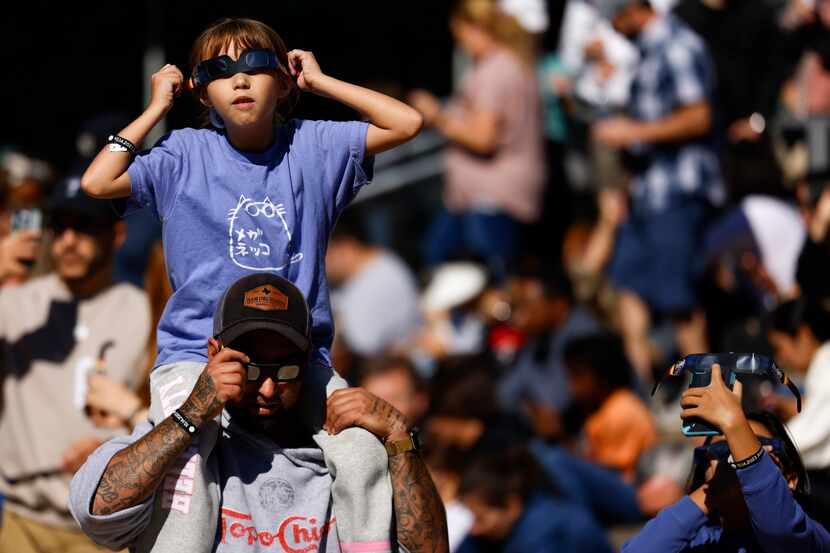 William Casarez carried his daughter Brianna, 9, during an eclipse watch event at the Perot...