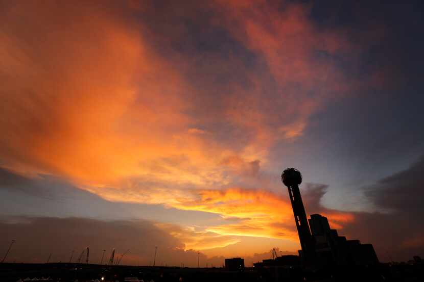 The sun sets behind Reunion Tower as approaching storms loom on the horizon, Friday evening,...