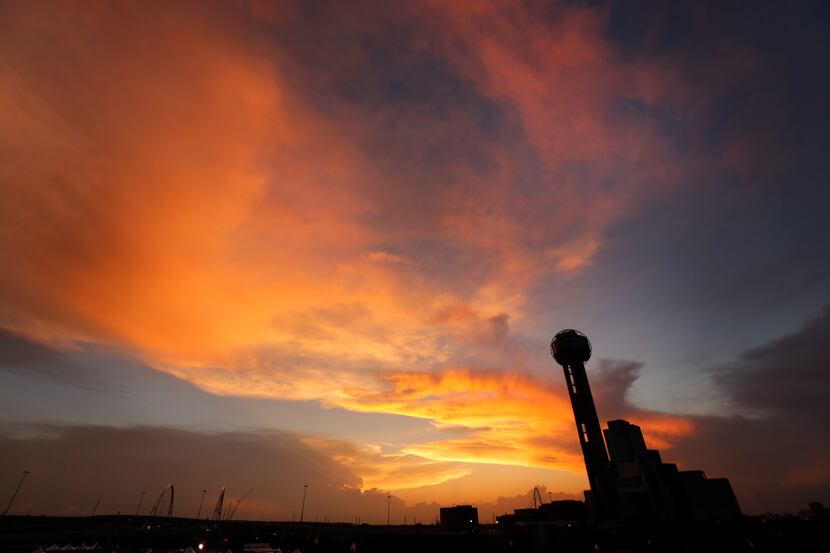 The sun sets behind Reunion Tower as approaching storms loom on the horizon, Friday evening,...