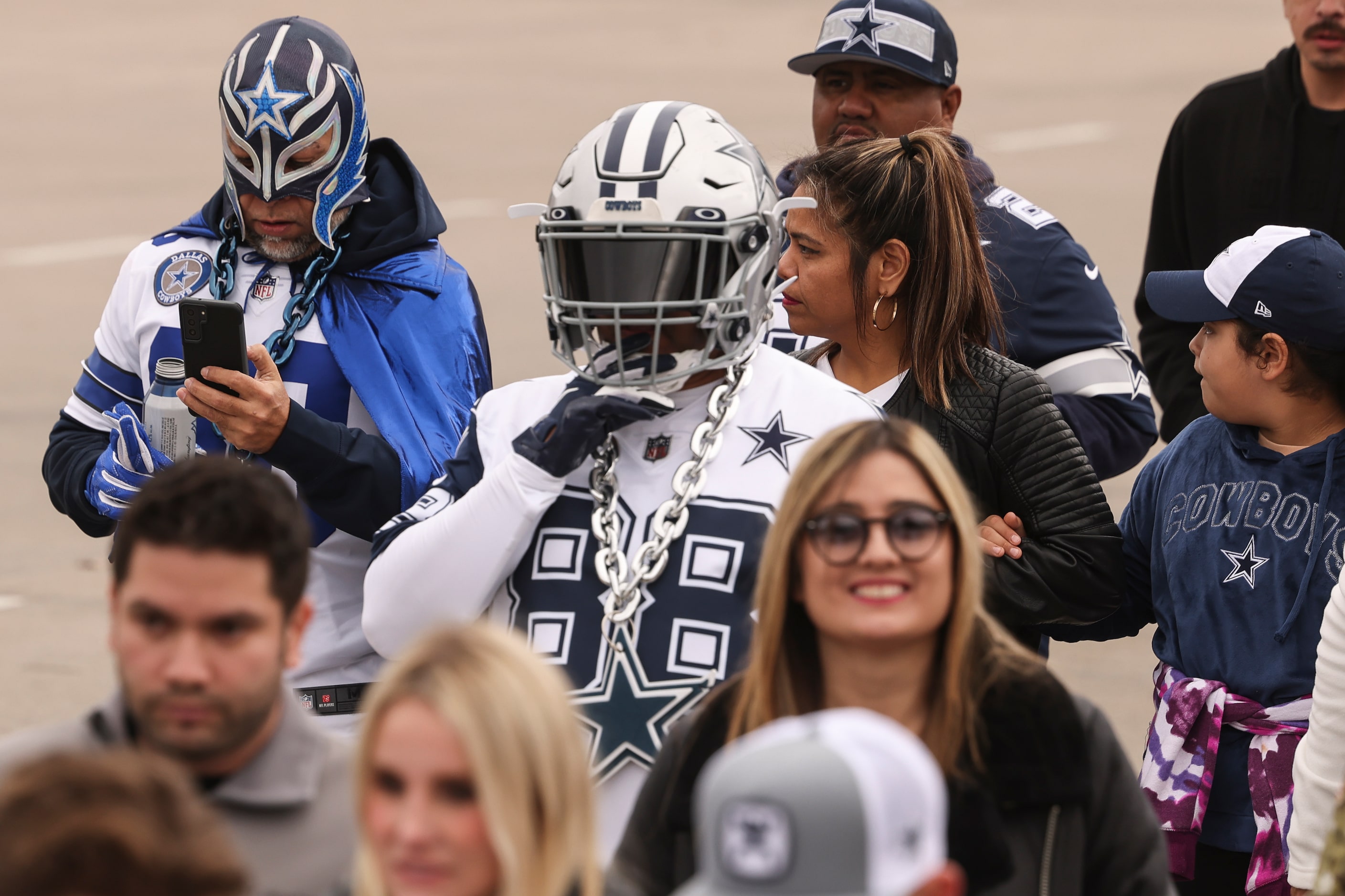 Jose Sammiguel and Marco Olivo walk across the street with other fans before the NFL game...