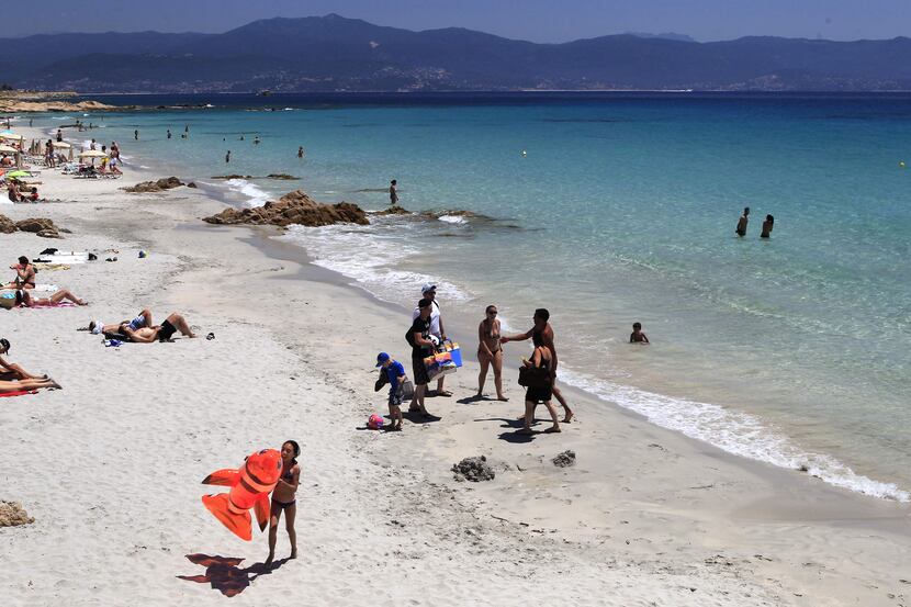 People stand on the beach in Ajaccio on June 25, 2016 on the French island of Corsica....