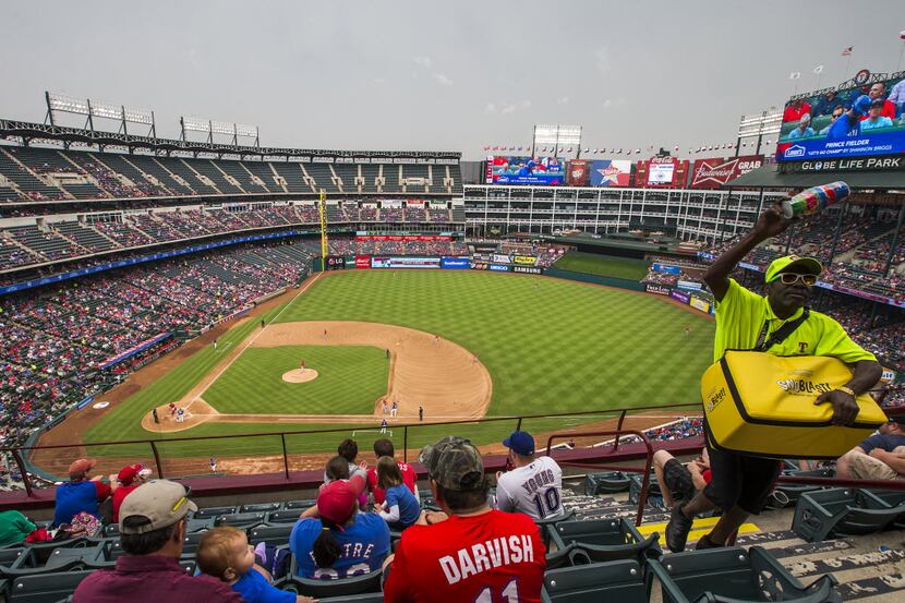 A vendor sells frozen treats while the Texas Rangers play the Los Angeles Angels as gray...