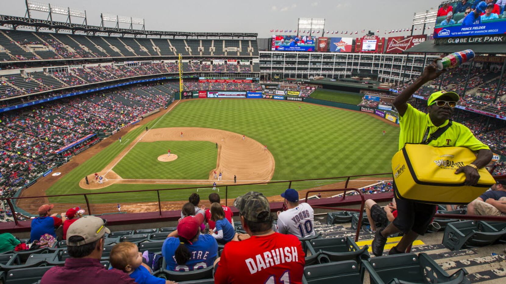 A vendor sells frozen treats while the Texas Rangers play the Los Angeles Angels as gray...