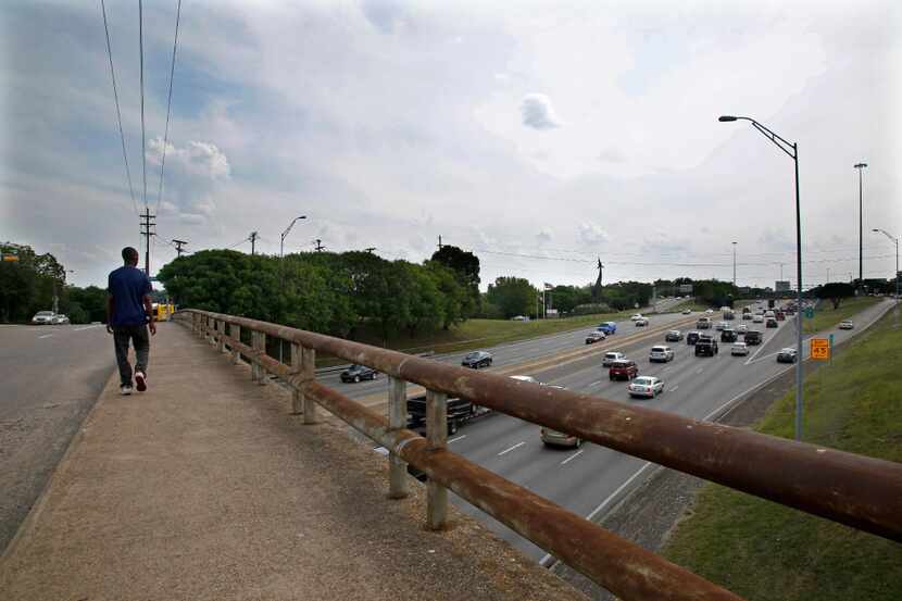 A pedestrian crosses the Ewing Street overpass as traffic from southbound I-35E exits at...