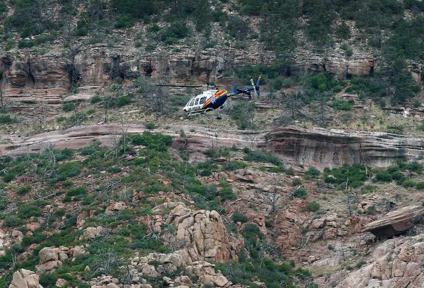 A helicopter flies above the rugged terrain along the banks of the East Verde River during a...