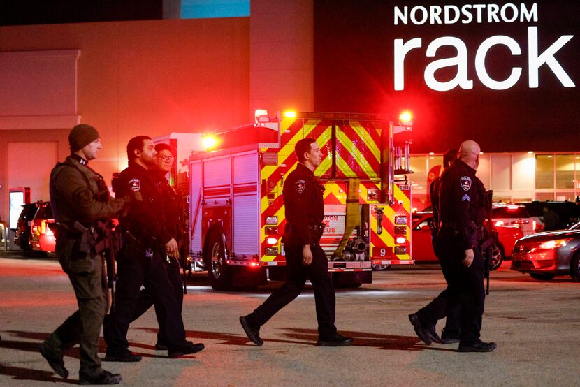 Arlington police officers walk through a parking lot as they work the scene after two people...