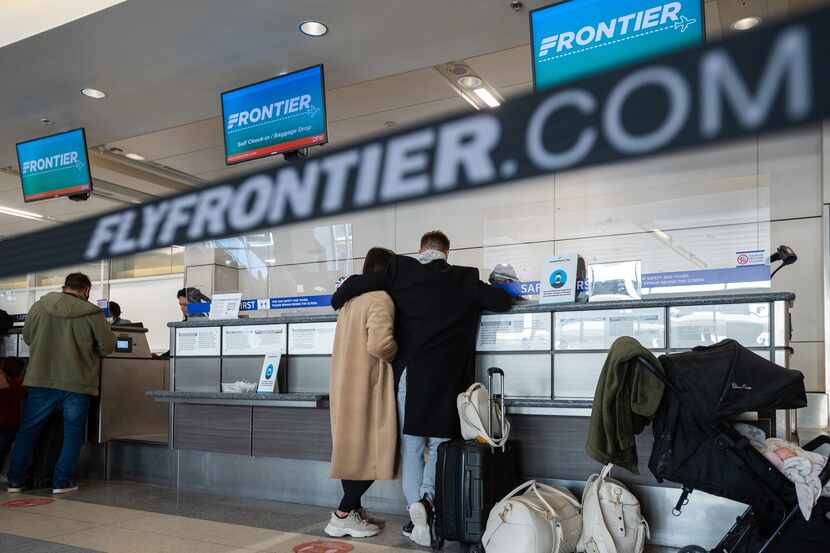 Passengers speak with Frontier customer service agents before boarding their flights at the...