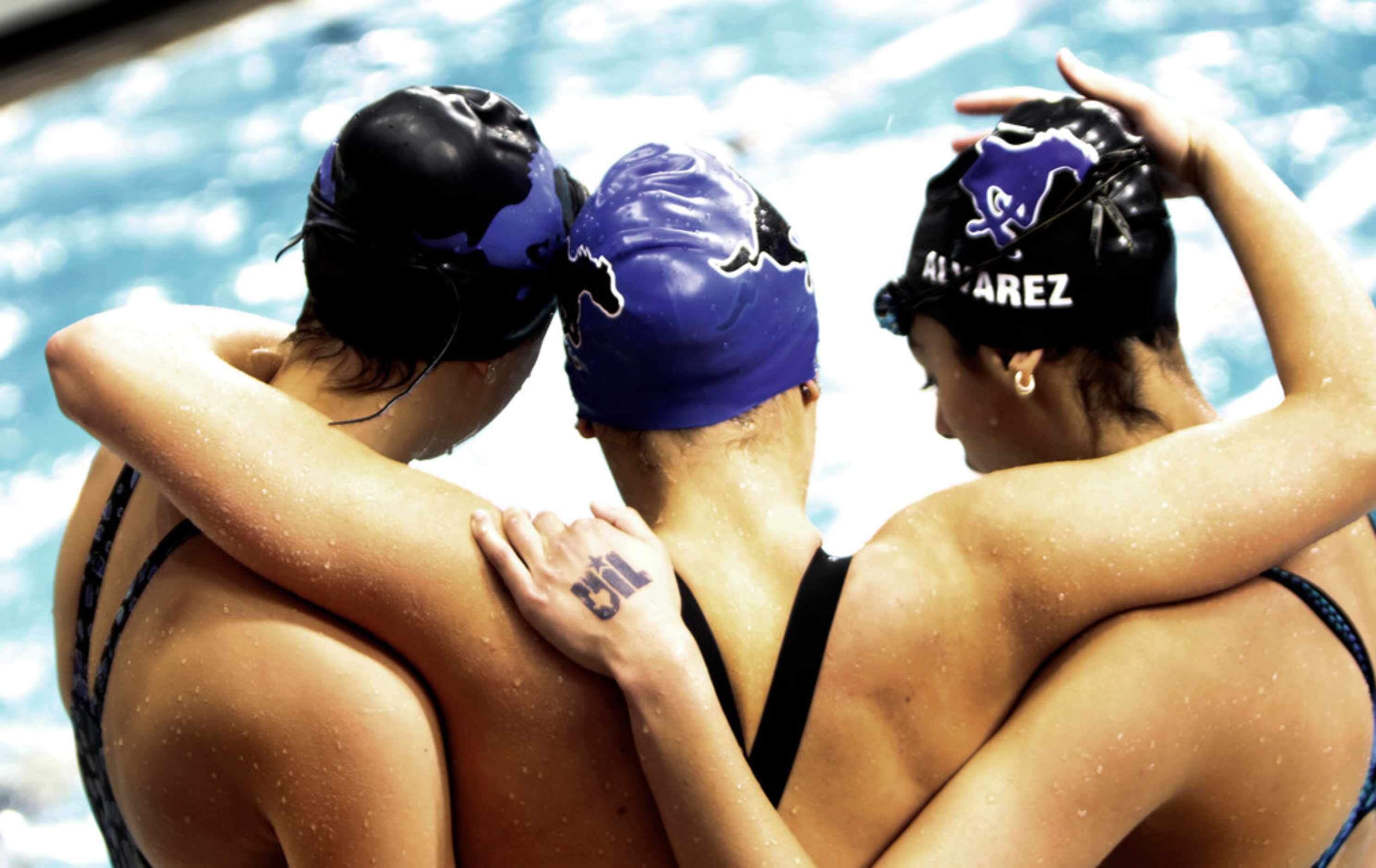 A trio of athletes hug following a swimming event. The UIL Class 6A state swimming and...