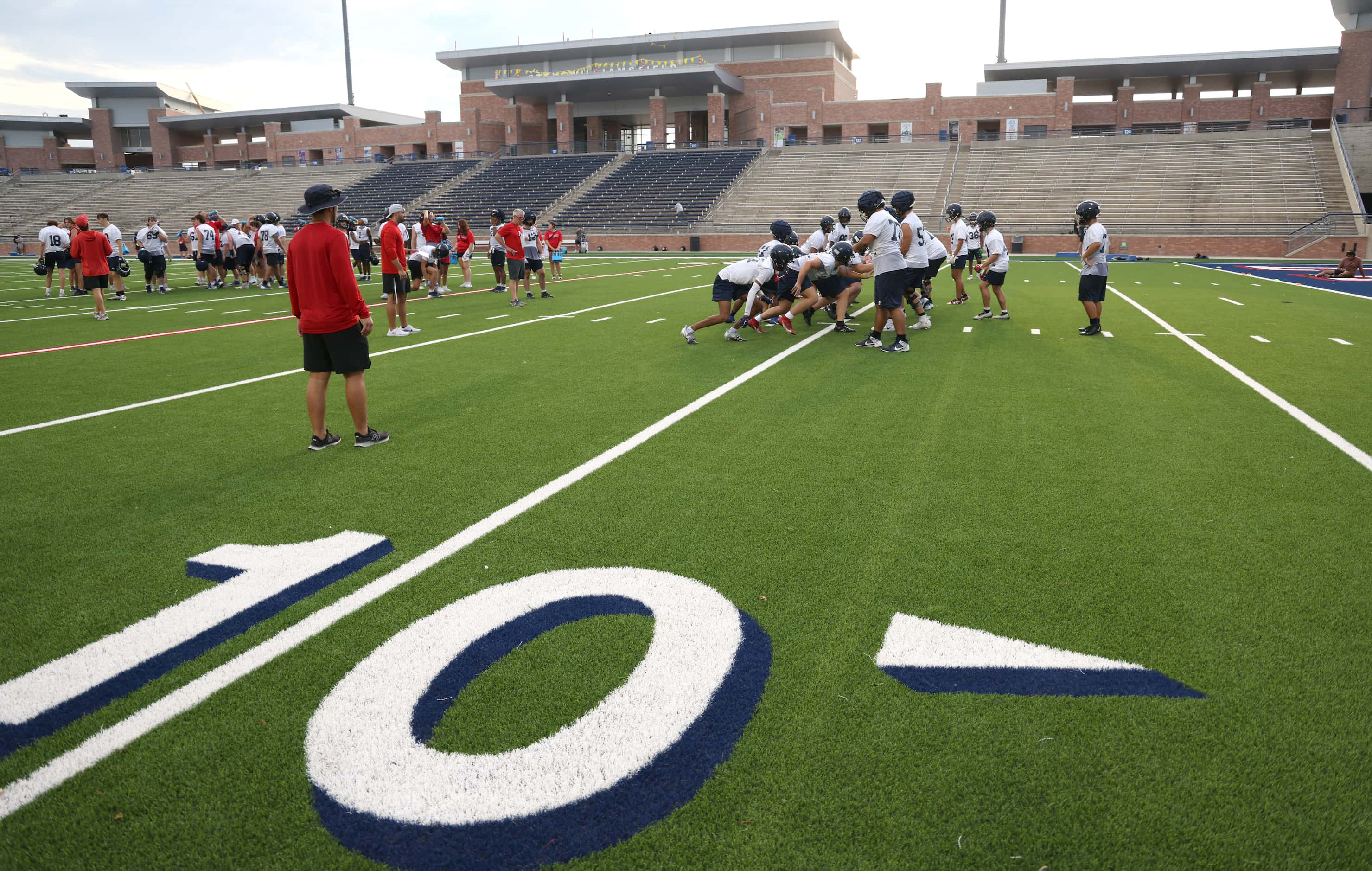 A group Allen Eagles assistant coaches lead the offensive line group through a drill during...